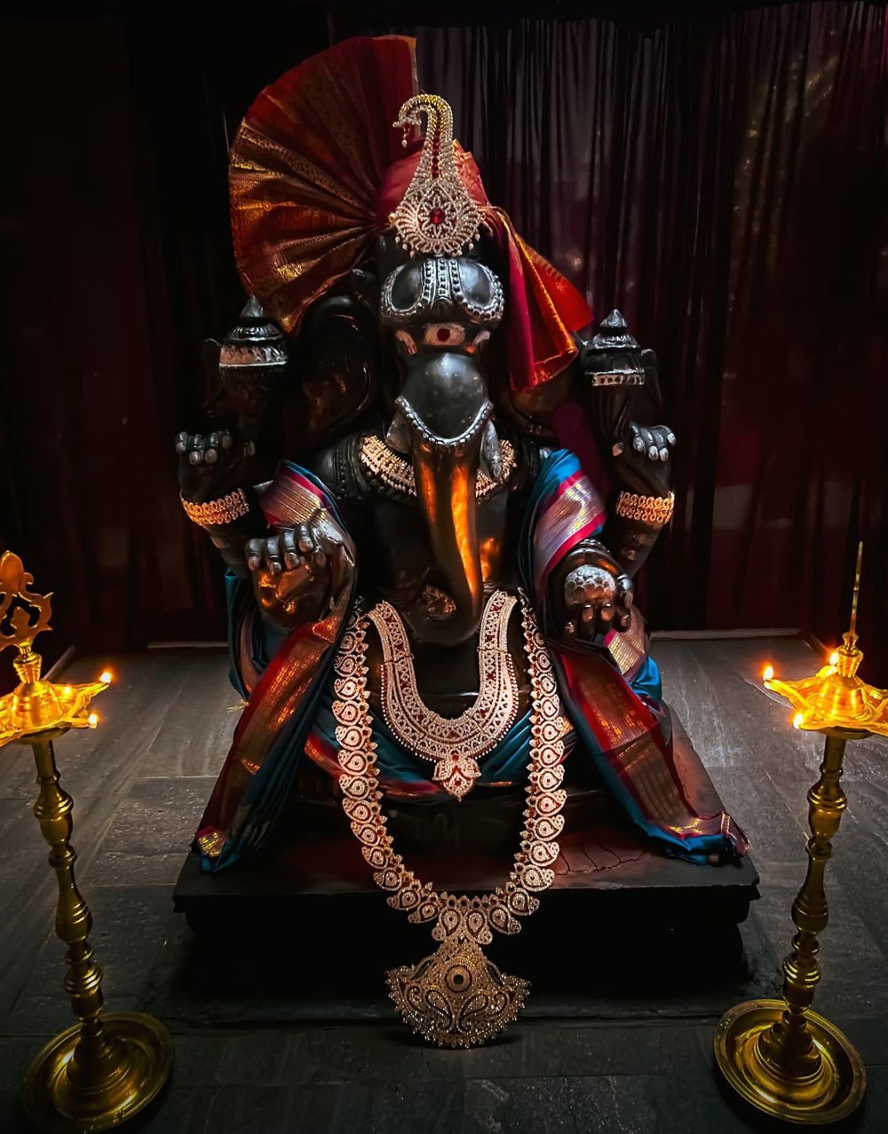 Sri Ananda Ganesha in alankaram with brass lamps