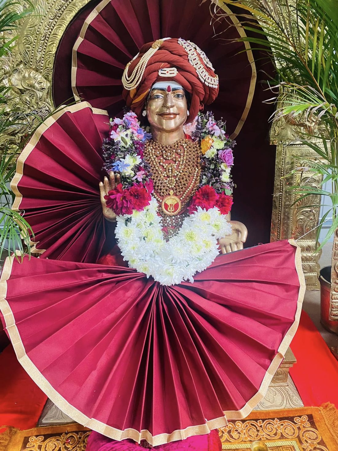 Deity of THE SPH JGM HDH Bhagavan Sri Nithyananda Paramashivam adorned with flowers and maroon silk at KAILASA Melbourne Sarvajnapeetam